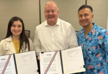 Evaluation of SCNX3 on India-Singapore Cable Plans worth $1b Three adults smile while holding open folders with official documents in a meeting room.