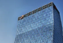 SK Telecom Puts Fabs from SK hynix in NVIDIA Omniverse Twin Tall blue glass skyscraper rising against a clear sky, viewed from below? (modern office building)