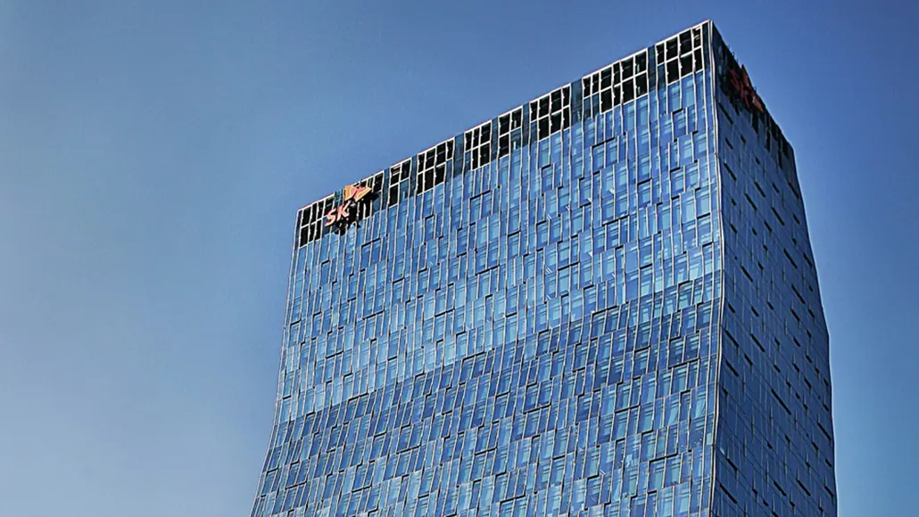 Tall blue glass skyscraper rising against a clear sky, viewed from below? (modern office building)