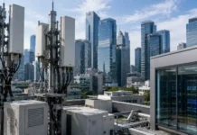 Telecom Operators Bet on AI RAN Technology to Lead the Global 6G Standards Race Rooftop with telecom antenna towers and cabinets, overlooking a downtown skyline of glass skyscrapers.