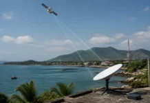 Starlink Launches Satellite Internet Service in Vietnam Satellite in orbit above a coastal landscape with a ground dish pointing toward it for communication signals.