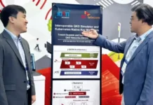 Digital Twin Technology Advances Quantum Network Testing Two men in suits discuss a poster about an interoperable QKD simulator and Kubernetes-native key managers in a conference setting.